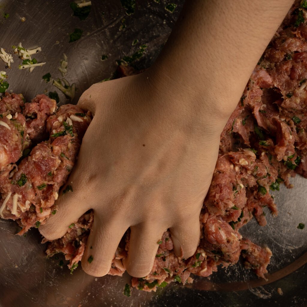 hand mixing ground meat and herbs in bowl 2026 03 09 22 32 52 utc